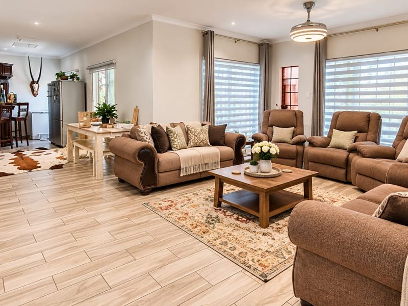 Spacious open-plan living area featuring wood-look tiled flooring, a cozy wood-burning fireplace, and a dedicated built-in bar area.