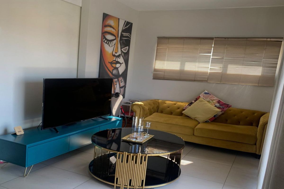 A well-lit living room featuring neutral tiled flooring and fitted venetian blinds, creating a comfortable and functional space.