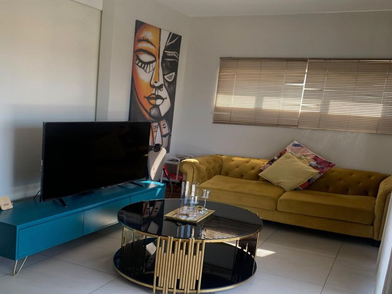 A well-lit living room featuring neutral tiled flooring and fitted venetian blinds, creating a comfortable and functional space.
