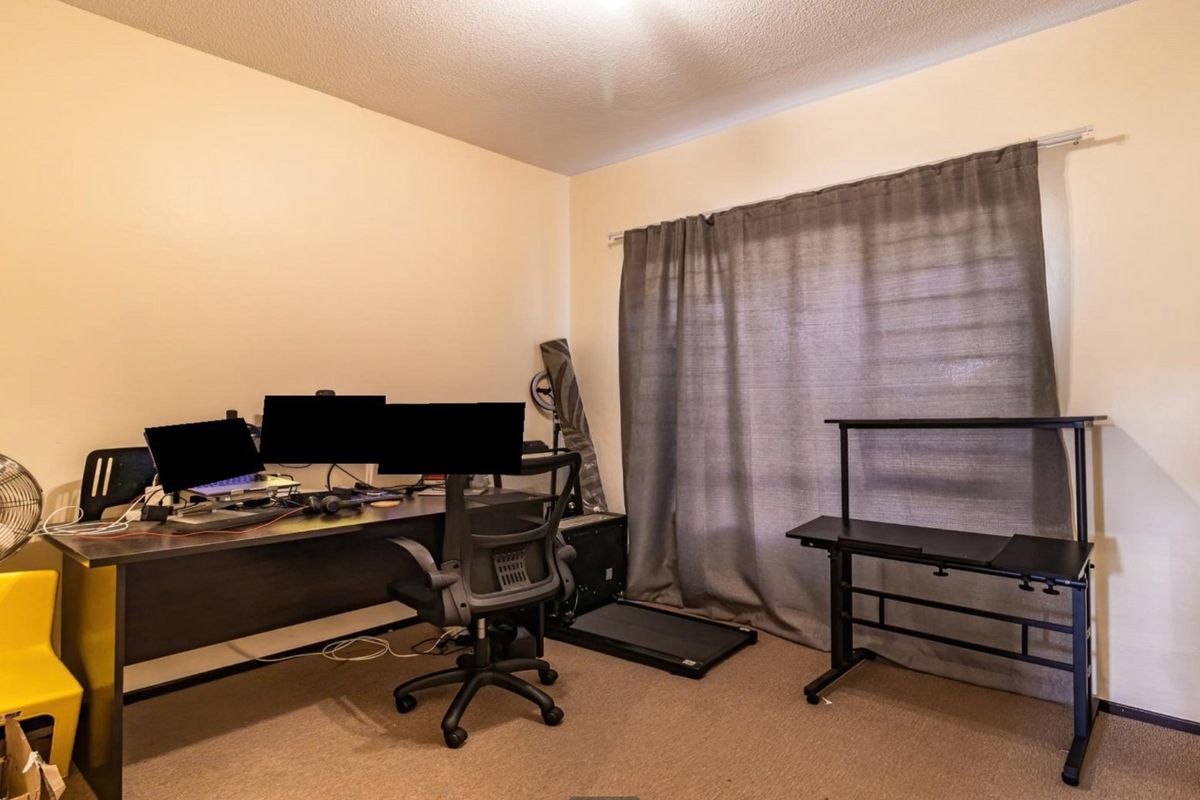 A functional bedroom space featuring neutral wall finishes, carpeted flooring, and a window fitted with a curtain rail.