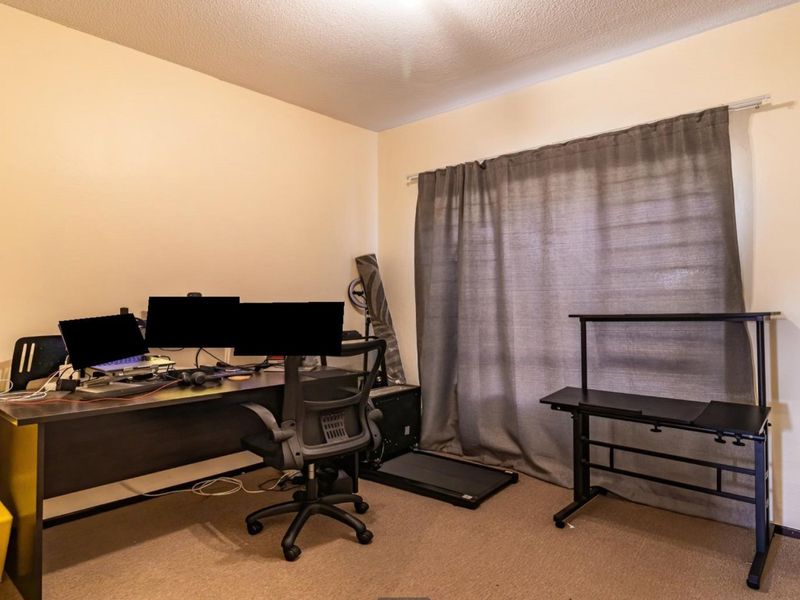 A functional bedroom space featuring neutral wall finishes, carpeted flooring, and a window fitted with a curtain rail.