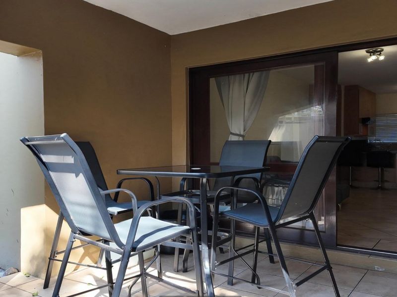 A covered patio area featuring tiled flooring and a large sliding glass door providing access to the interior living space.