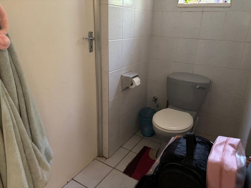 A functional bathroom featuring tiled walls and flooring with a standard toilet installation.
