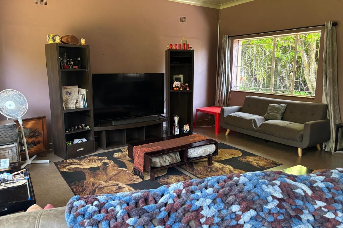 A living room featuring tiled flooring, security bars on the window, and neutral wall tones, offering a functional space with potential for modernization.