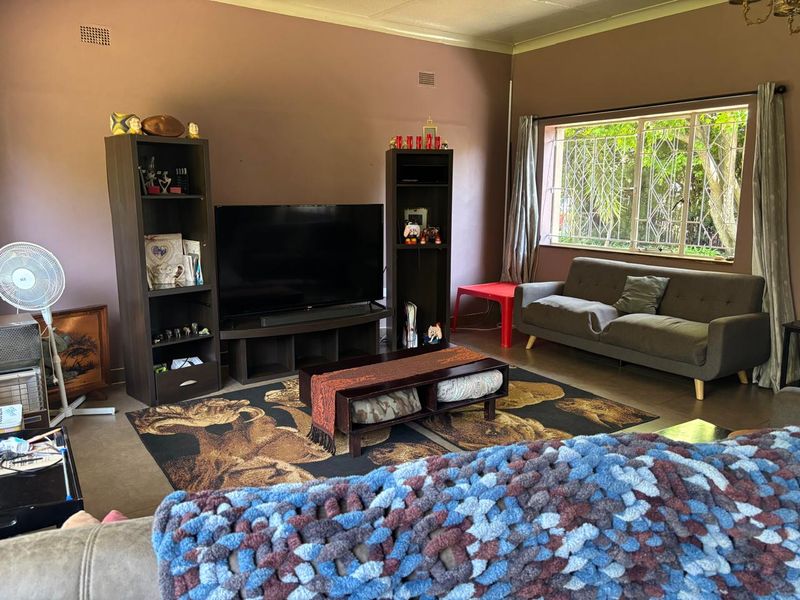A living room featuring tiled flooring, security bars on the window, and neutral wall tones, offering a functional space with potential for modernization.