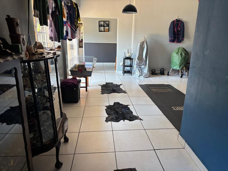 A spacious living area featuring neutral tiled flooring and a central pendant light, offering a versatile layout for various furniture arrangements.