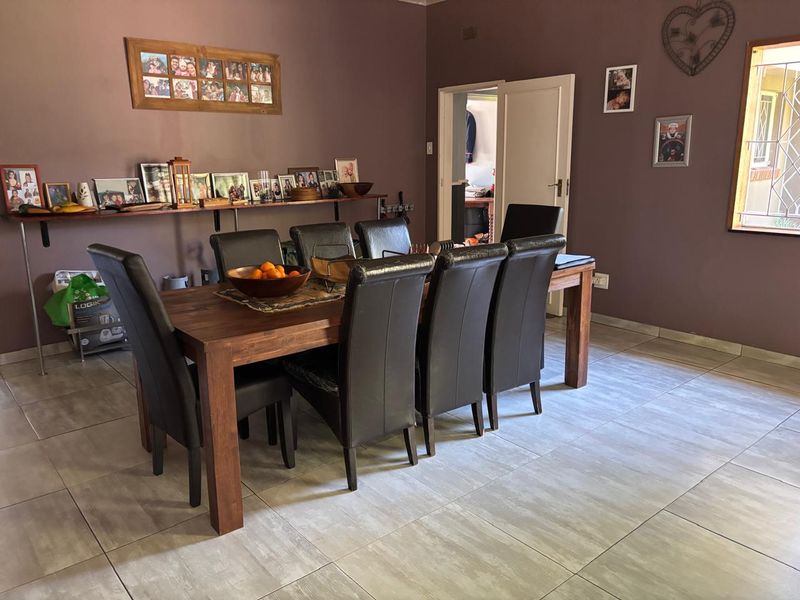 A dining room featuring large format floor tiles and a built-in wall-mounted display shelf.