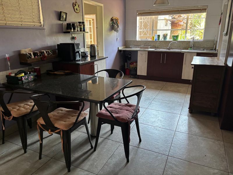 A functional kitchen featuring granite countertops, double basin sink, and tiled flooring, offering a practical layout with potential for modern cosmetic updates.