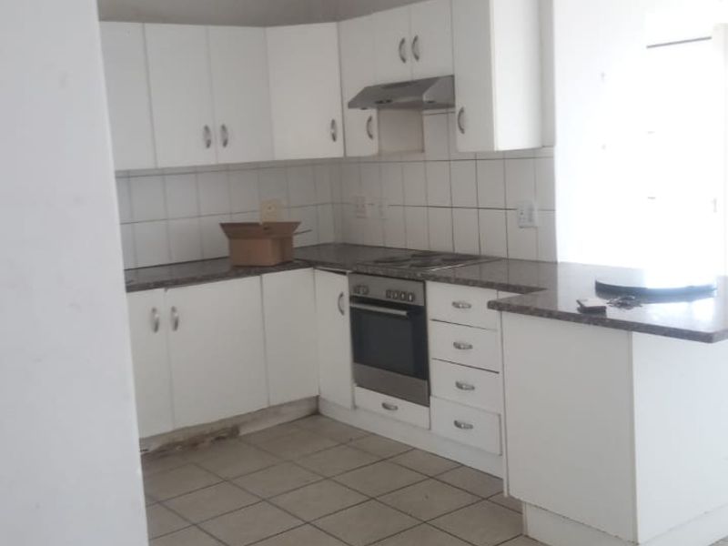 A functional kitchen featuring white built-in cabinetry, laminate countertops, a built-in oven with extractor fan, and tiled flooring throughout.