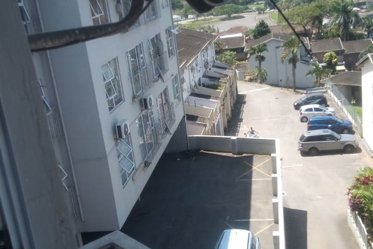 Elevated view overlooking the apartment complex parking area and surrounding neighborhood from a balcony.