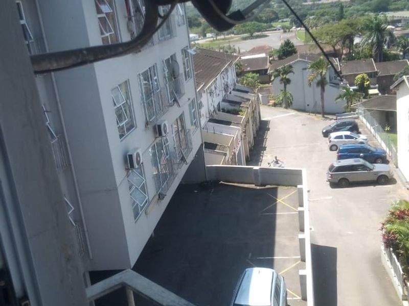 Elevated view overlooking the apartment complex parking area and surrounding neighborhood from a balcony.