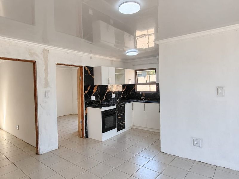 Open plan kitchen area featuring modern cabinetry and marble-effect splashback, requiring final wall finishing and trim work to complete the space.