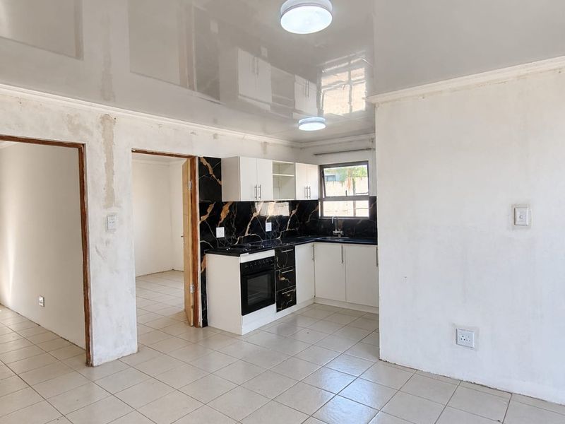 Open plan kitchen area featuring modern cabinetry and marble-look splashback, set within a space requiring final wall finishing and plastering.