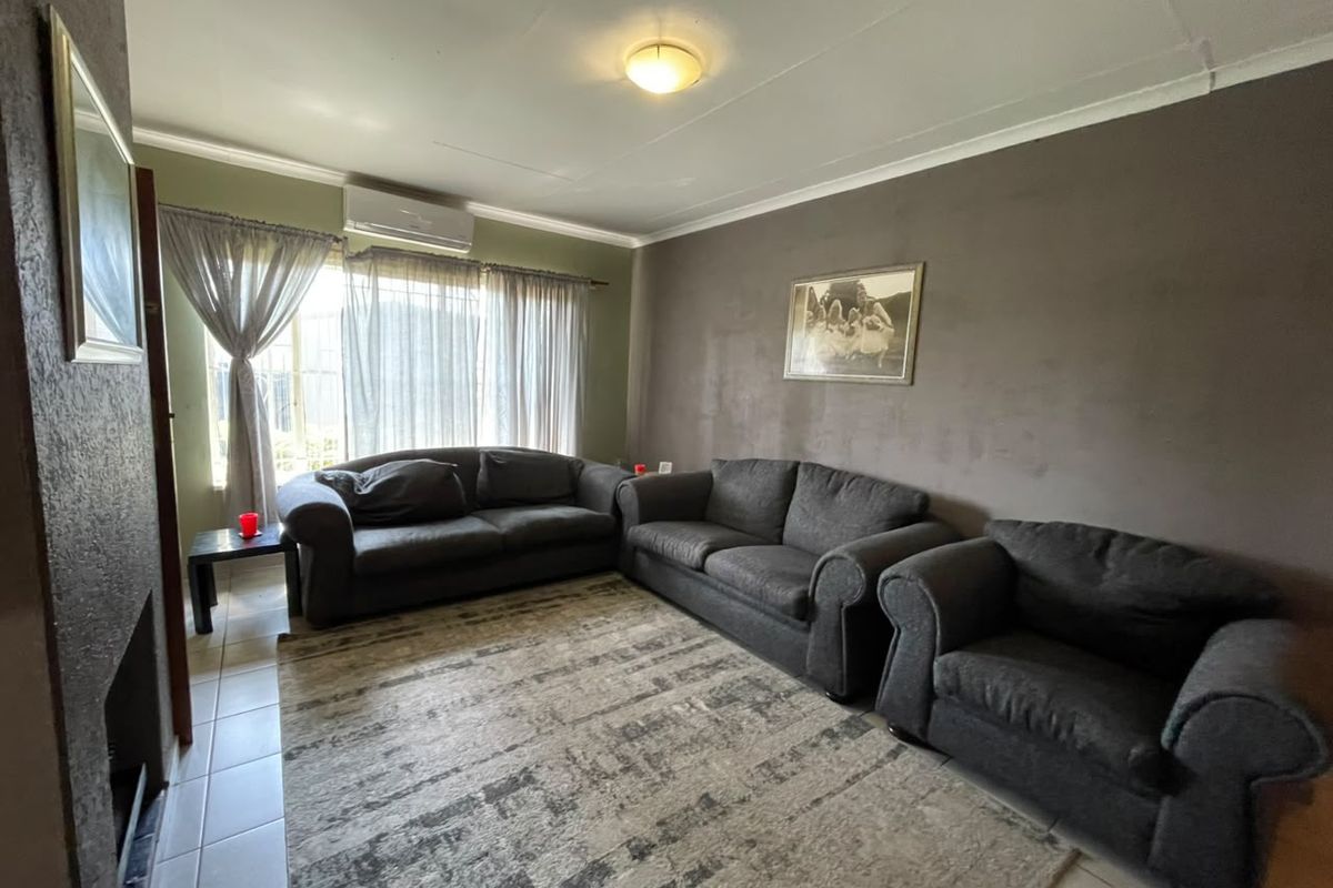 A living room featuring tiled flooring, a fireplace, and an installed air conditioning unit, offering a functional space with potential for cosmetic updates.