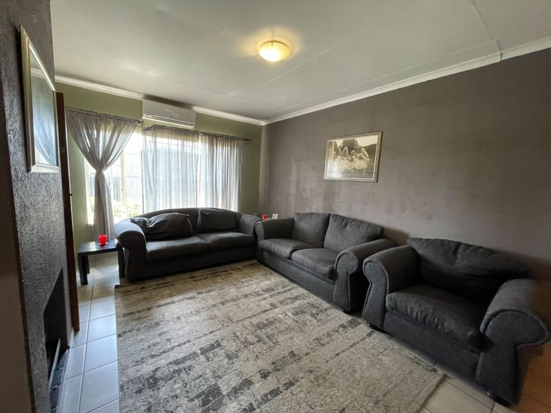 A living room featuring tiled flooring, a fireplace, and an installed air conditioning unit, offering a functional space with potential for cosmetic updates.