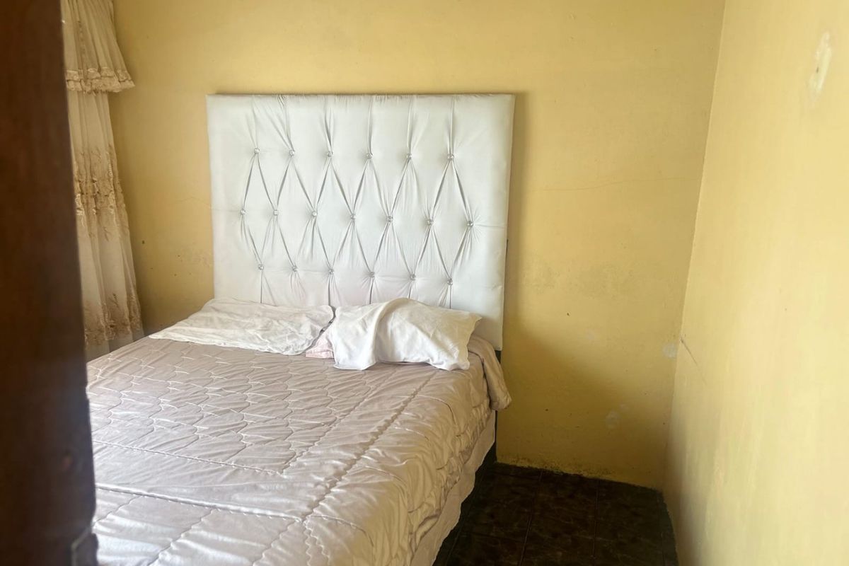 A bedroom featuring tiled flooring and yellow painted walls in need of cosmetic attention.