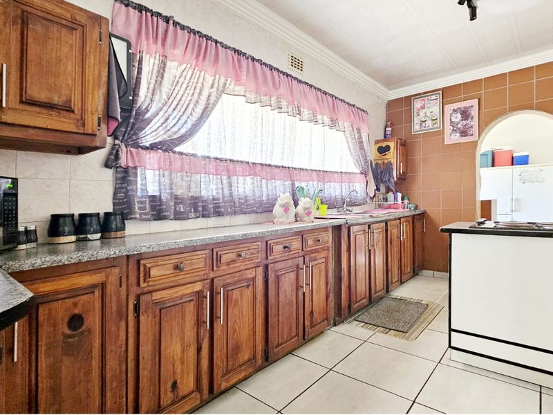A functional kitchen featuring traditional wooden cabinetry, granite countertops, tiled backsplash, and tiled flooring, offering a classic layout with ample storage space.
