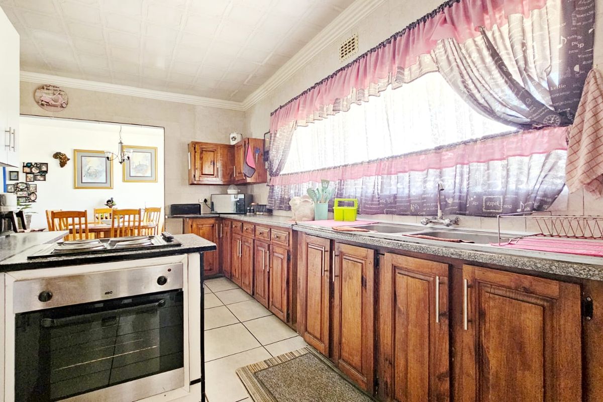 A functional kitchen featuring traditional wooden cabinetry, granite countertops, a built-in oven, and a double sink, offering a classic layout with potential for modernization.