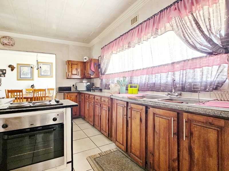 A functional kitchen featuring traditional wooden cabinetry, granite countertops, a built-in oven, and a double sink, offering a classic layout with potential for modernization.