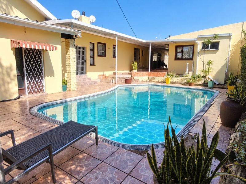 Outdoor pool area featuring a tiled patio, swimming pool, and covered patio space with security gates.