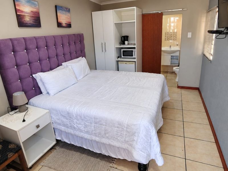A bedroom featuring tiled flooring, a built-in wardrobe, and an attached en-suite bathroom with a sliding door entry.