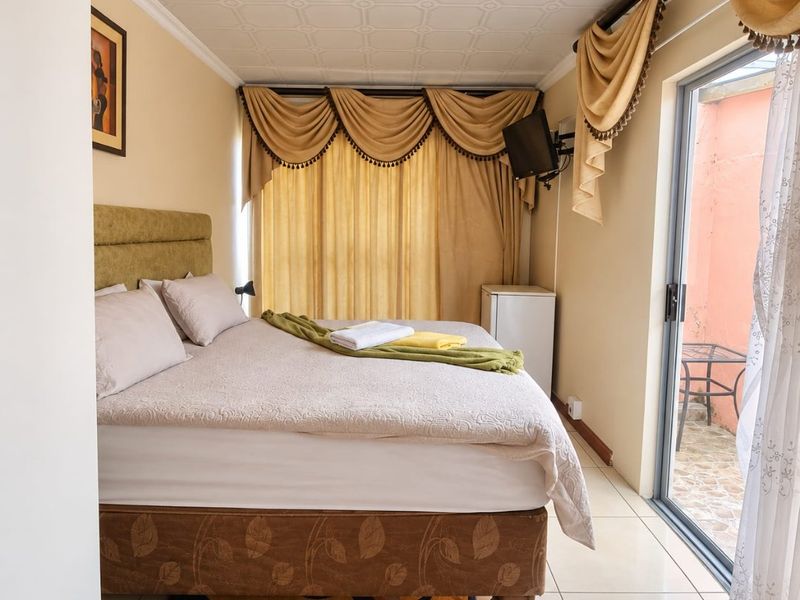 A bedroom featuring tiled flooring, a textured ceiling, and a sliding glass door providing access to an outdoor area.