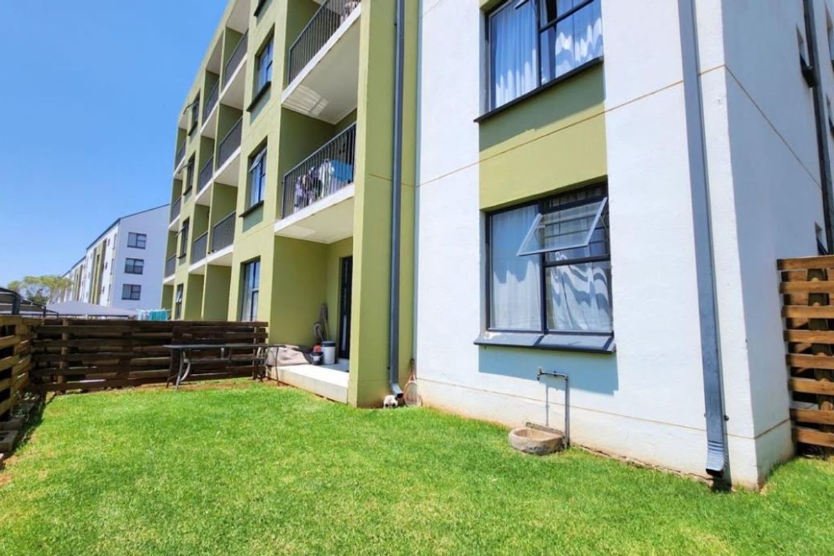 Ground floor apartment exterior featuring a private garden area, timber fencing, and access to a balcony with metal railings.