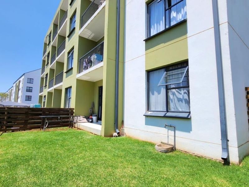 Ground floor apartment exterior featuring a private garden area, timber fencing, and access to a balcony with metal railings.