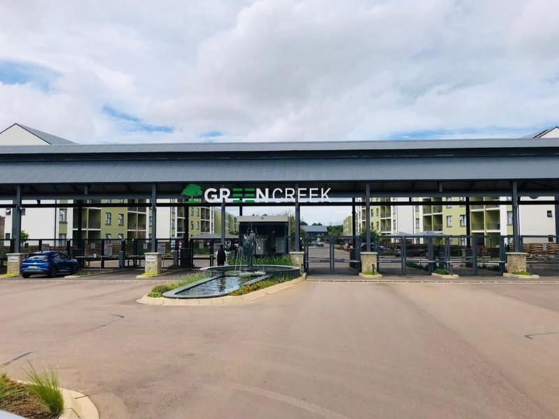 The main entrance to Greencreek estate featuring a secure gated access point, guard house, and a landscaped water feature.
