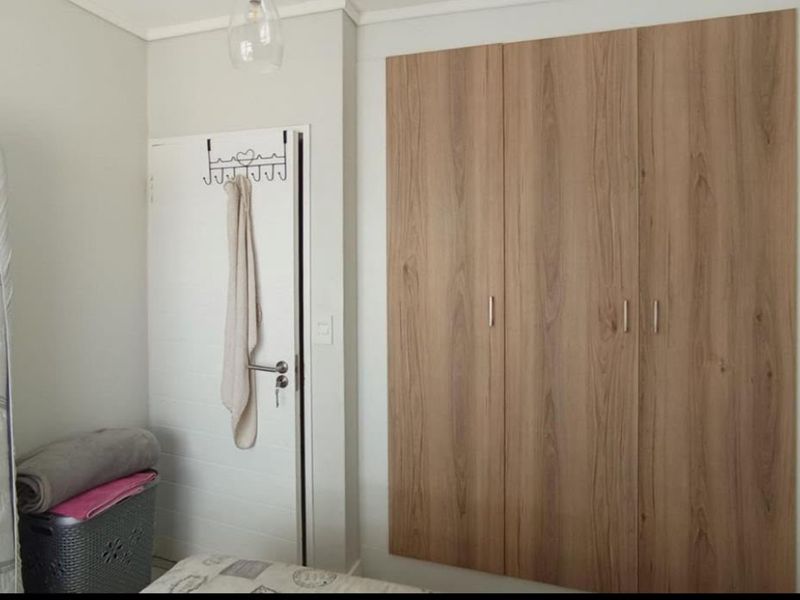 A bedroom featuring modern wood-finish built-in wardrobes and a standard internal door.