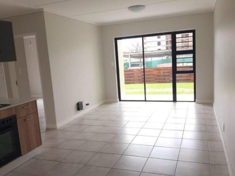 Open-plan living area featuring tiled floors, a modern kitchen with built-in appliances, and large sliding doors leading to an outdoor space.