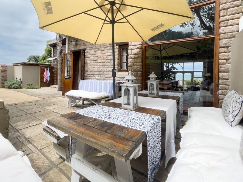 A charming outdoor patio area featuring stone-clad walls, paved flooring, and large sliding glass doors that provide seamless access to the interior living space.
