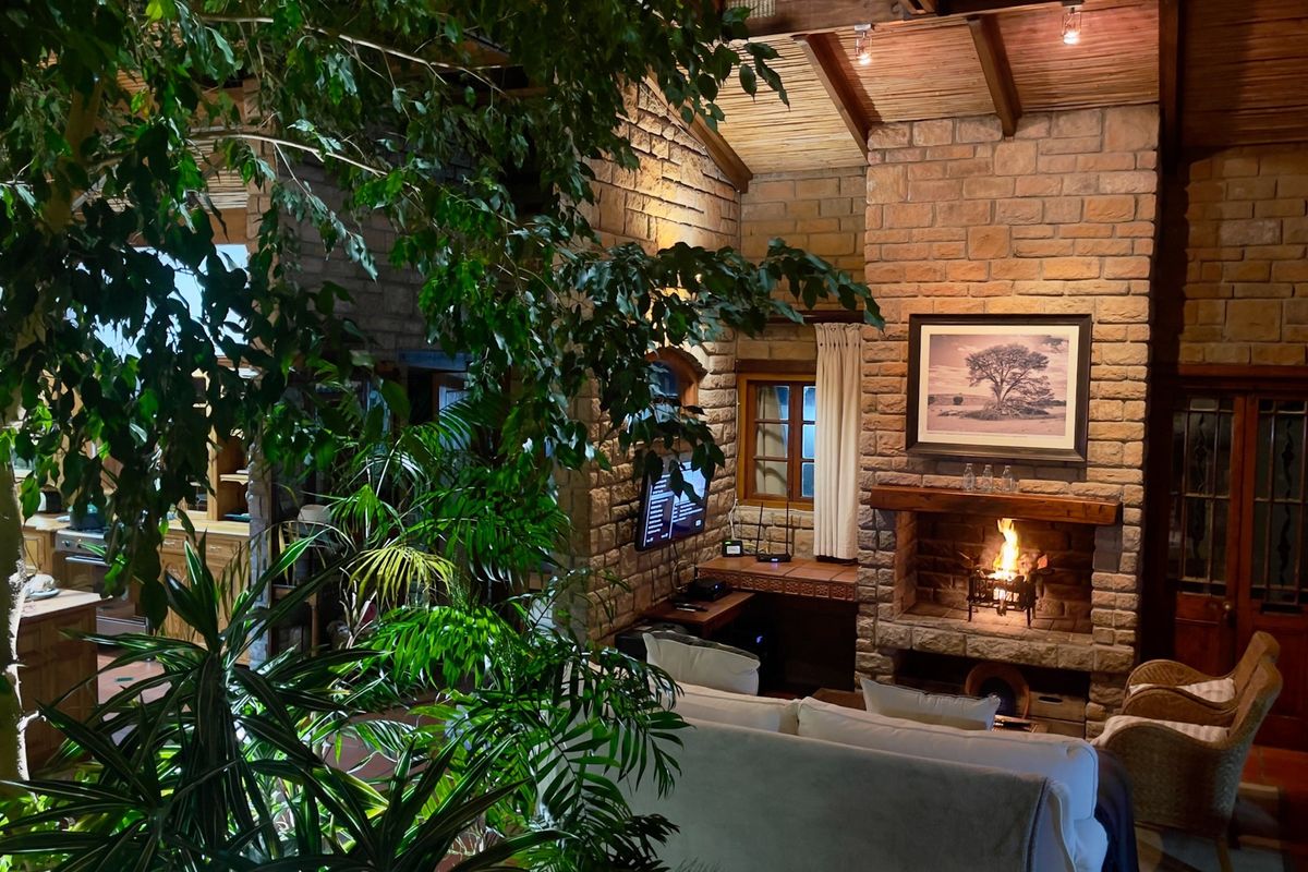 Cozy living room featuring a prominent stone fireplace, exposed timber beam ceiling, and rustic stone wall finishes, creating a warm and inviting atmosphere.