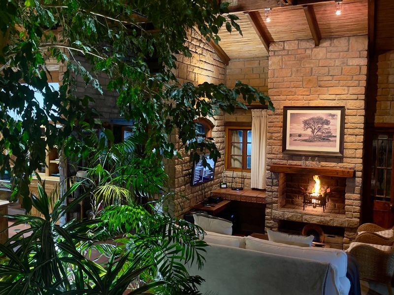 Cozy living room featuring a prominent stone fireplace, exposed timber beam ceiling, and rustic stone wall finishes, creating a warm and inviting atmosphere.