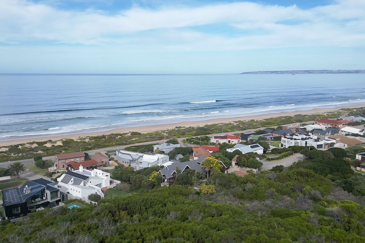 An elevated aerial view of a coastal residential neighborhood situated along the beach, showcasing the surrounding landscape and proximity to the ocean.