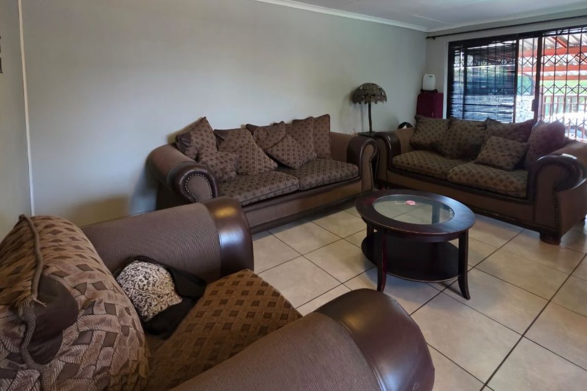 A spacious living room featuring neutral wall tones, ceramic floor tiles, and a sliding glass door providing access to the outdoor area.
