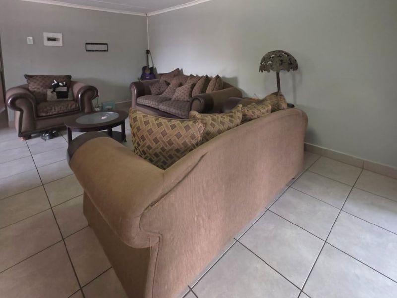 A spacious living room featuring neutral wall tones and tiled flooring throughout, providing a blank canvas for personalization.