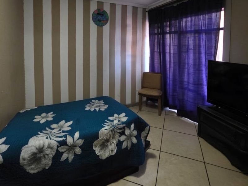 A bedroom featuring tiled flooring and a sliding door with curtains, providing access to the exterior.