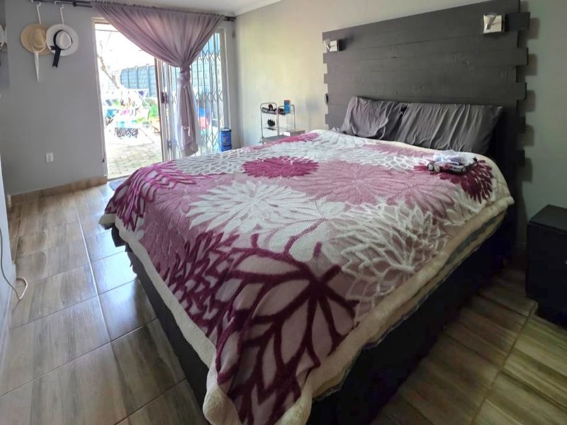 A bedroom featuring tiled flooring and a sliding glass door with security gate providing direct access to the outdoor area.