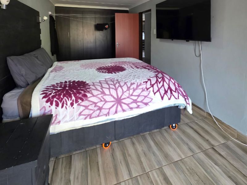 A bedroom featuring tiled flooring, built-in cupboards, and a wall-mounted television.