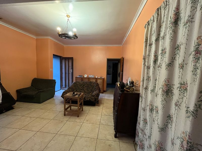 A living room featuring tiled flooring and orange painted walls, providing a functional space with potential for modern updates.