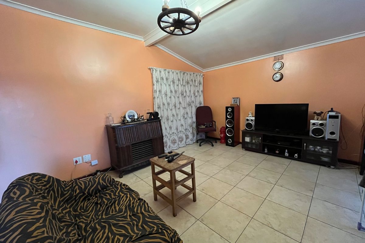 A spacious living room featuring tiled flooring and a coved ceiling, offering a blank canvas for modern updates and interior design improvements.