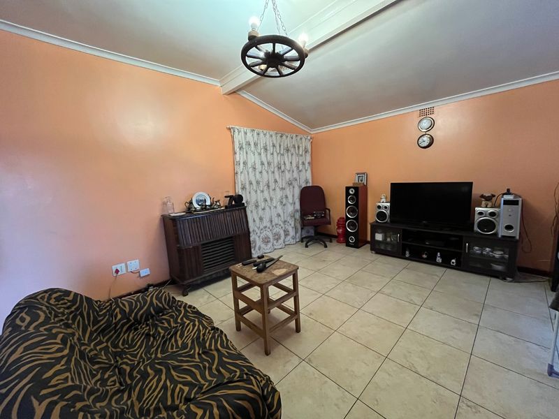 A spacious living room featuring tiled flooring and a coved ceiling, offering a blank canvas for modern updates and interior design improvements.