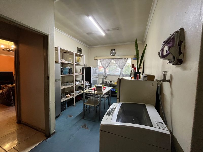 A functional laundry area featuring a wall-mounted water connection and basic utility space, currently showing signs of wear and requiring cosmetic updates.