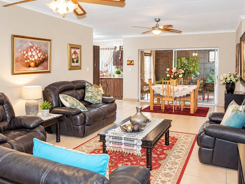 Spacious open-plan living and dining area featuring tiled flooring, ceiling fans, and large sliding glass doors leading to an enclosed patio.