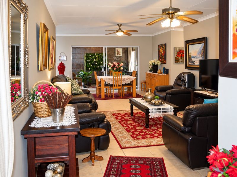 Spacious open-plan living and dining area featuring tiled flooring, ceiling fans, and large sliding glass doors leading to an outdoor patio space.