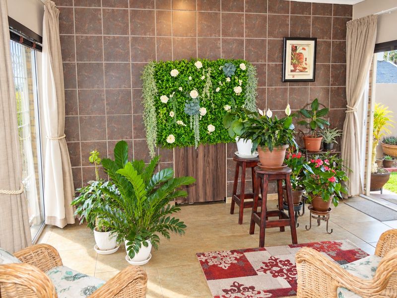 A bright, enclosed patio area featuring tiled flooring and a decorative tiled feature wall, with large sliding glass doors providing access to the garden.