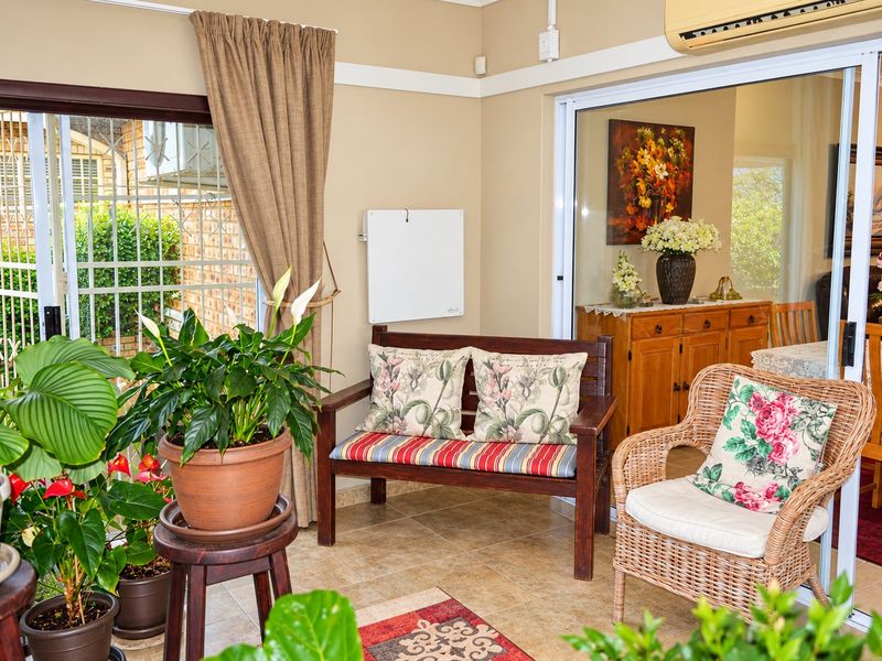A bright, enclosed patio area featuring tiled flooring, sliding glass doors with security gates, and wall-mounted climate control units for year-round comfort.