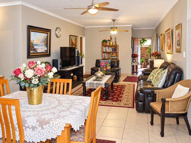 Spacious open-plan living and dining area featuring neutral wall tones, tiled flooring, and dual ceiling fans, providing a comfortable and functional layout.
