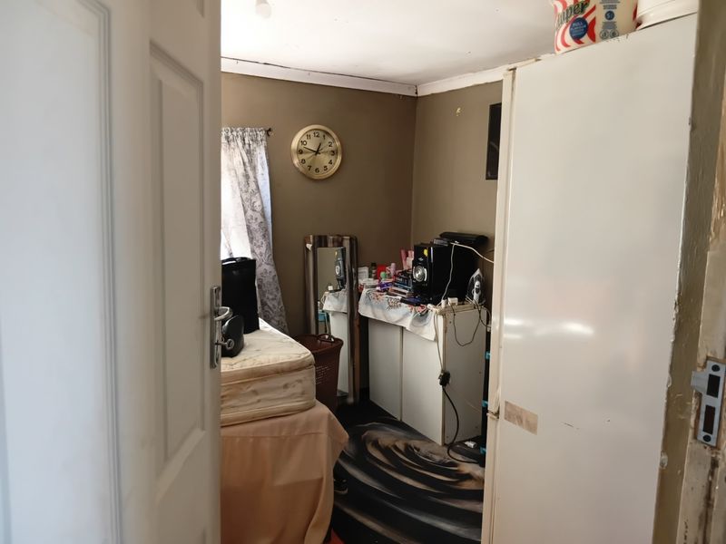 A small bedroom space requiring cosmetic updates, featuring a window and internal door access.
